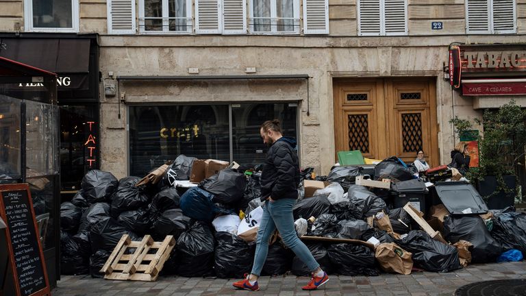 FILE- A man walks past uncollected garbage in Paris, Monday, March 13, 2023. The City of Light is losing its luster with tons of garbage piling up on Paris sidewalks as sanitation workers strike for a ninth day. (AP Photo/Lewis Joly, File)