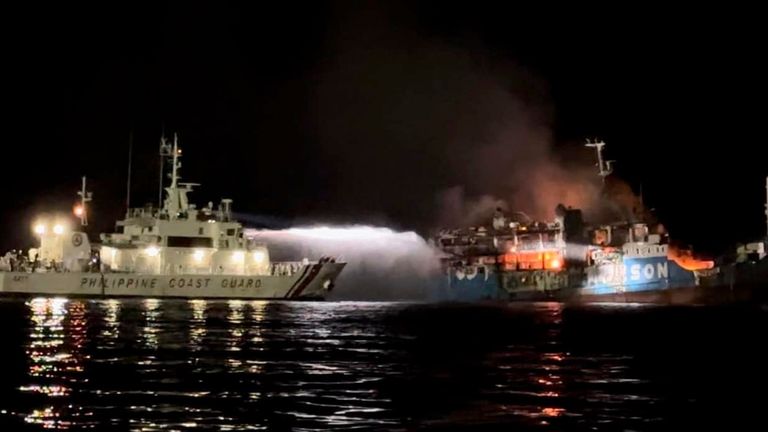 En esta foto proporcionada por la Guardia Costera de Filipinas, un barco de la Guardia Costera de Filipinas está entrenando su manguera mientras intenta extinguir un incendio en el MV Lady Mary Joy.