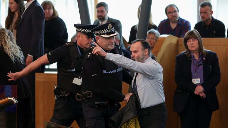 Police officers remove a protestor during the First Minister&#39;s Questions at the Scottish Parliament at Holyrood, in Edinburgh, Scotland, Britain, March 30, 2023. REUTERS/Russell Cheyne