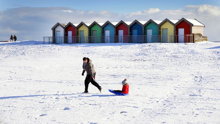 A woman pulls a child on a sledge through the snow at Blyth in Northumberland