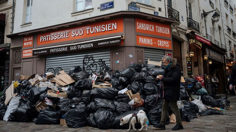 A man walks past piles of garbage in Paris, Monday, March 13, 2023. A contentious bill that would raise the retirement age in France from 62 to 64 got a push forward with the Senate&#39;s adoption of the measure amid strikes, protests and uncollected garbage piling higher by the day. (AP Photo/Lewis Joly)
