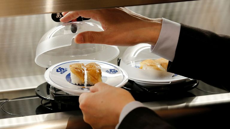 A man picks up a sushi from conveyor belt during a media event a day before the official opening of Kura Sushi&#39;s new branch in Tokyo, Japan