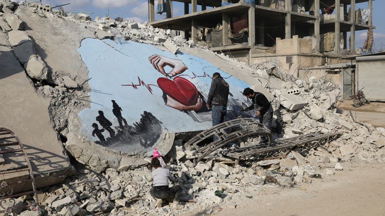 Syrian artist Aziz Asmar paints street art on the rubble of damaged buildings in the rebel-held town of Jandaris, Syria 