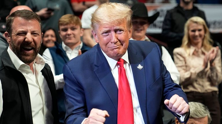 Former President Donald J. Trump gestures to Vito Arujau, NCAA wrestling champion at the 133 lb class, at the NCAA Wrestling Championships, Saturday, March 18, 2023, in Tulsa, Okla. At left if U.S. Sen. Markwayne Mullin. (AP Photo/Sue Ogrocki)