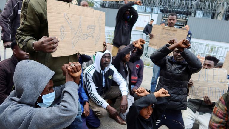 African migrants gesture and carry banners during a protest asking for evacuation from Tunisia
