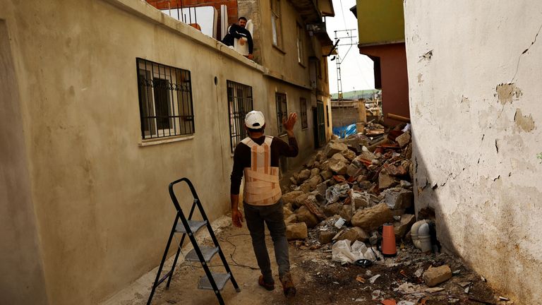 Rami Shaymusa, 30, waves to a neighbour as he walks to his damaged home in the aftermath of the deadly earthquake in Bozhoyuk, Turkey