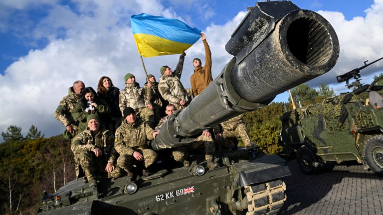 Ukrainian personnel pose with a flag on top of a Challenger 2 tank during a training at Bovington Camp, near Wool in southwestern Britain, February 22, 2023. REUTERS/Toby Melville