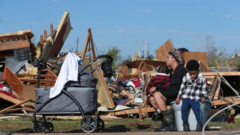 Melanie Childs sits on a bucket and holds her two children as they view whats left of her grandfather's home in Armory. Pic: AP