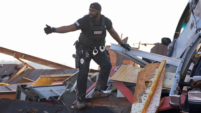 A sheriff&#39;s deputy gives the all-clear signal after climbing onto a piled up vehicle to search for survivors at Chuck&#39;s Dairy Bar in Rolling Fork. Pic: AP