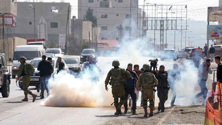 Palestinian journalists flee as Israeli soldiers fire tear gas in the West Bank town of Huwara Pic: AP 