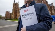 A man holds a copy of the Queen&#39;s University Belfast Agreement Twenty Five programme