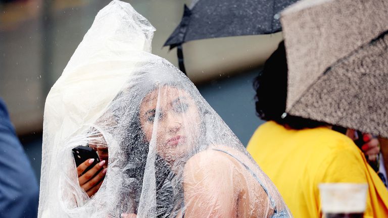 Horse Racing - Grand National Festival 2023 - Aintree Racecourse, Liverpool, Britain - April 14, 2023 .A racegoer shields herself from the rain on Ladies Day REUTERS/Phil Noble