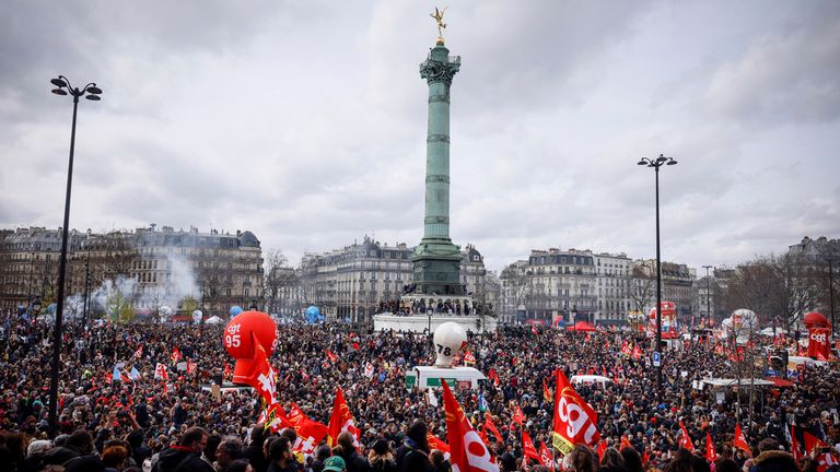 23 Mart 2023 Perşembe, Paris'teki bir miting sırasında Place de la Bastille'de toplanan protestocular. Fransız sendikaları, Başkan Emmanuel Macron'un parlamentoda oylama olmaksızın emeklilik yaşını yükseltmeye zorlayarak halkın öfkesini alevlendirmesinden bu yana Perşembe günü ilk toplu gösterilerini düzenliyorlar.  Fransa Cumhurbaşkanı Emmanuel Macron'u tasvir eden pankart solda, "benim emekli maaşım seninkinden önce."(AP Fotoğrafı/Thomas Padilla)