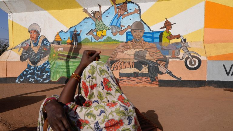 FILE - A woman looks at a mural in Ouagadougou, Burkina Faso, on March 1, 2023. Burkina Faso&#39;s government has opened investigations into allegations of human rights abuses by its security forces after a video surfaced that appeared to show the extrajudicial killing of seven children in the country&#39;s north. AP
