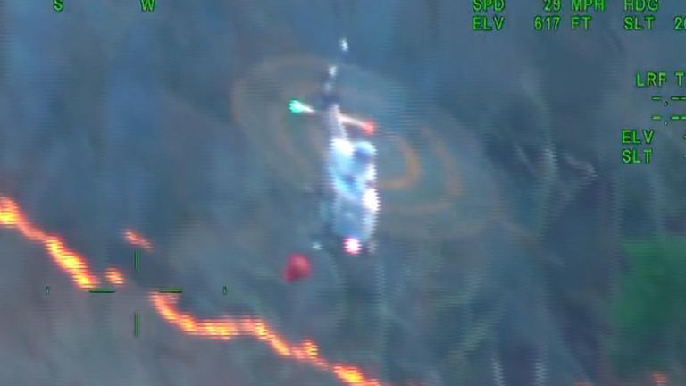 Troopers in Massachusetts assist firefighters using a helicopter to drop buckets of water on a spreading wildfire. 