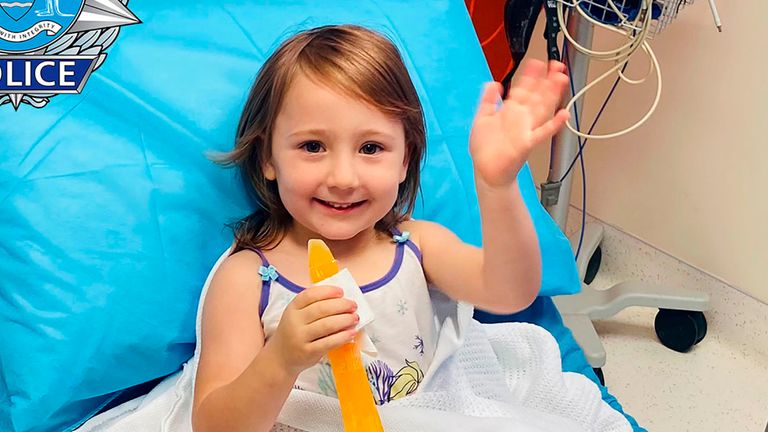 Cleo Smith waves as she sits on a bed in hospital after she was found by police