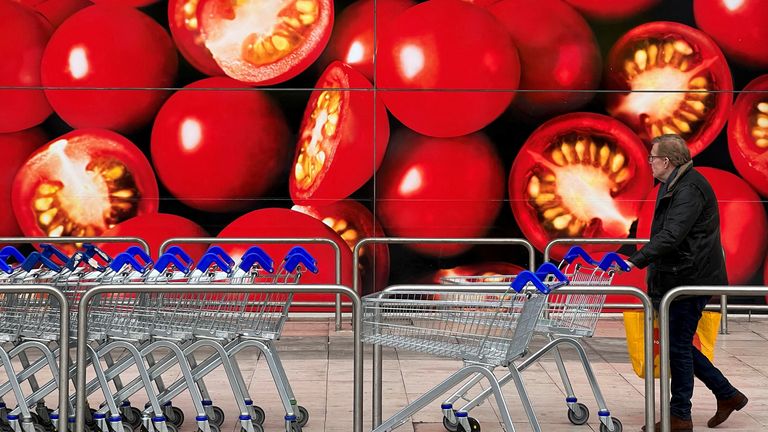 FILE PHOTO: A shopper walks next to a photographic depiction of tomatoes on a Tesco supermarket as Britain experiences a seasonal shortage of some fruit and vegetables, in London, Britain, February 26, 2023. REUTERS/Toby Melville/File Photo