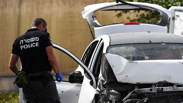 An Israeli policeman checks a damaged car at the scene of a shooting  in the Jordan Valley in the Israeli-occupied West Bank 