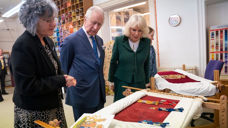 The King and Queen Consort look at their throne seat covers during a visit to the Royal College of Needlework at Hampton Court Palace in East Molesey, Surrey
