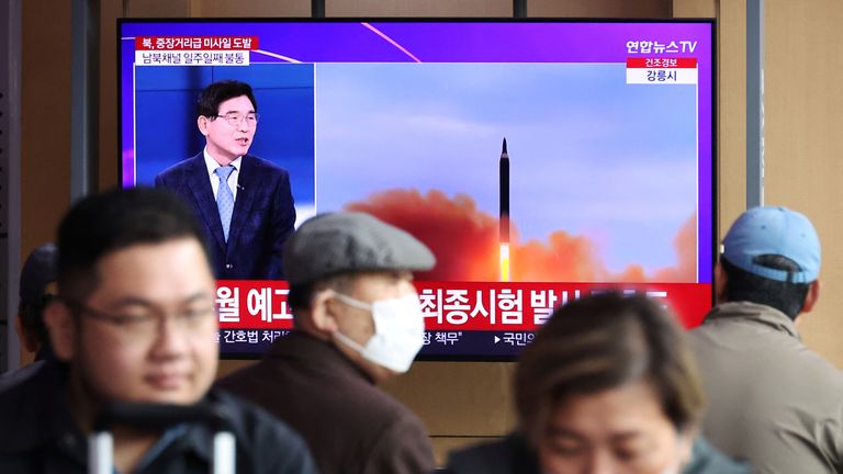 İnsanlar Kuzey Kore'nin Güney Kore'nin Seul kentindeki bir tren istasyonuna balistik füze fırlatmasıyla ilgili bir haber izliyor.