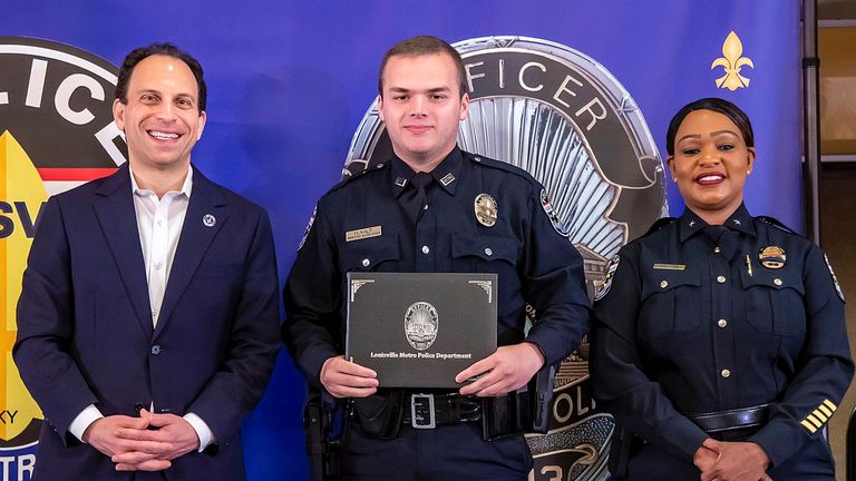 In this photo provided by the Louisville Metro Police Department, from left, Louisville Mayor Craig Greenberg, Officer Nickolas Wilt and Louisville Metro Interim Police Chief Jacquelyn Gwinn-Villaroel pose for a photo, in Louisville, Ky., March 31, 2023. Wilt was shot while responding to a call where a bank employee armed with a rifle opened fire at his workplace early Monday, April 10. (Louisville Metro Police Department via AP)