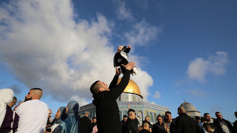 Bir Filistinli, Kudüs'ün Eski Kenti'nde, Müslümanlar tarafından Kutsal Mabet ve Yahudiler tarafından Tapınak Dağı olarak bilinen Mescid-i Aksa'nın bulunduğu yerleşkede Ramazan Bayramı namazını müteakip bir çocukla oynarken kutlama yapıyor, 21 Nisan 2023 REUTERS/Jamal Awad TEKRAR SATIŞ YOK.  ARŞİV YOK