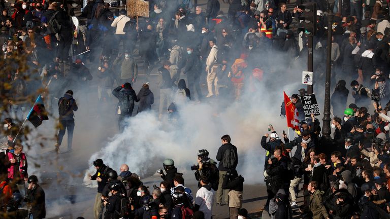 People react amid tear gas during clashes at a demonstration as protesters gather on Place de la Bastille in Paris