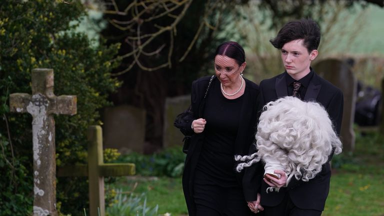 Daughter of Paul O&#39;Grady, Sharyn Mousley, with an unidentified young man carrying holding the wig of Lily Savage arriving for the funeral of Paul O&#39;Grady at St Rumwold&#39;s Church in Aldington, Kent. Roland H says he&#39;s happy to say it&#39;s O&#39;Grady&#39;s grandson