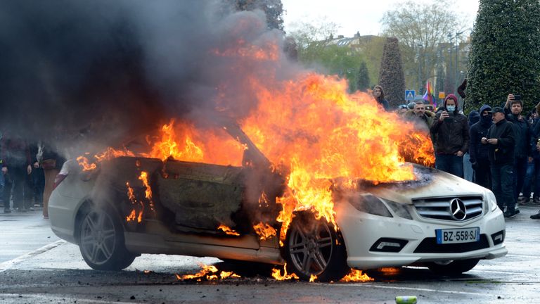 Protesters watch a burning car during a demonstration Thursday, April 13, 2023 in Rennes, western France. Protesters opposed to President Emmanuel Macron&#39;s unpopular plan to raise the retirement age in France marched Thursday in cities and towns around France in a final show of anger before a decision on whether the measure meets constitutional standards. (AP Photo/Mathieu Pattier)