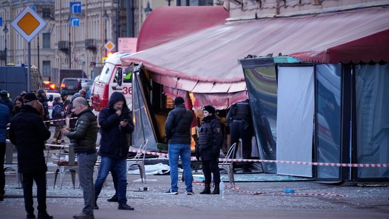 Russian investigators and police officers stand at the side of an explosion at a cafe in St Petersburg, Russia