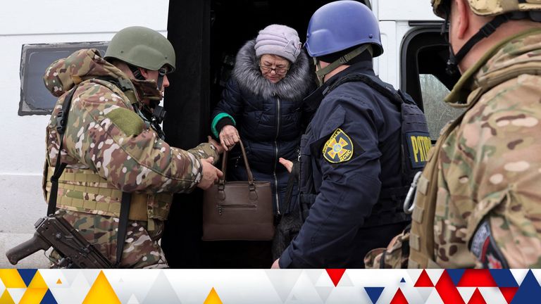 Halyna, 73, is helped by members of the Donetsk Police Department and the Ukrainian Emergency Services out of a vehicle, at a meeting point in an undisclosed location after being evacuated from the bombed-out frontline city of Avdiivka by the first and being handed over to the latter to be taken to a Dnipro bound train, amid Russia&#39;s attack on Ukraine, in the eastern region of Donetsk