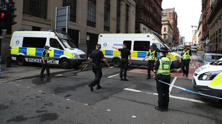 Police close off a road in Glasgow near the scene in West George Street, Glasgow, where a man was shot by an armed officer after another officer was injured during an attack.