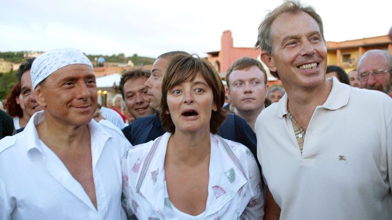 Italian Premier Silvio Berlusconi, left, sporting a print bandanna on his head and a white, loose-fitting shirt with matching white shoes and trousers, goes for a walk British Prime Minister Tony Blair, right, and his wife Cherie Blair, after their arrival at Berlusconi&#39;s luxury villa, in Porto Rotondo on the Island-region of Sardinia, Italy, Monday Aug. 16, 2004.  
Pic:AP