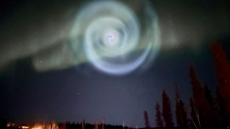 A light baby blue spiral resembling a galaxy appears amid the aurora for a few minutes in the Alaska skies