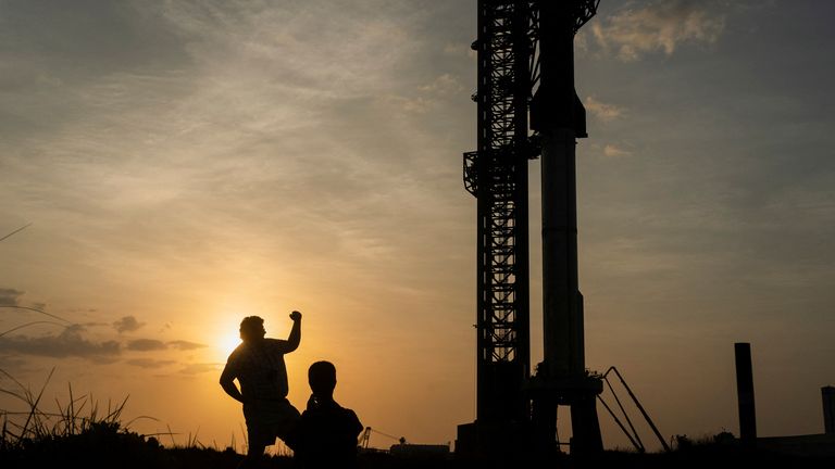 A person poses for a photo near the SpaceX Starship on its Boca Chica launchpad following a postponement in its launch date due to a frozen valve 