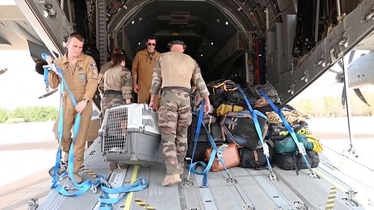 In this image provided by the French Armed Forces, military personnel load belongings of evacuees onto a plane at the airport in Khartoum