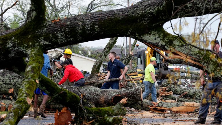 Sherwood, Ark. Police and firefighters are helped by volunteers to clear fallen trees on Keihl Avenue after a storm swept through the area, Friday, March 31, 2023