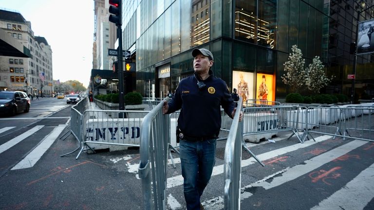 A New York police officer places a barricade around Trump Tower ahead of the hearing. Pic: AP