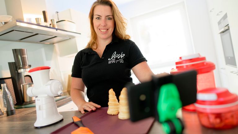 ILLUSTRATION - 08 May 2020, North Rhine-Westphalia, Cologne: Daniela Sigmund demonstrates kitchen utensils for a virtual Tupperware party in a set scene. The party manager uses digital distribution channels to advertise her goods. Photo by: Henning Kaiser/picture-alliance/dpa/AP Images