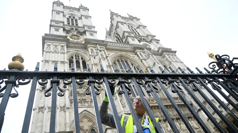 A worker outside Westminster Abbey paints railings in preparation of the coronation