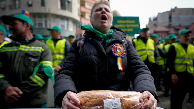 A woman holds a loaf of bread during a farmers&#39; protest in front of the Representative Office of the European Commission in Bucharest, Romania. Pic: AP