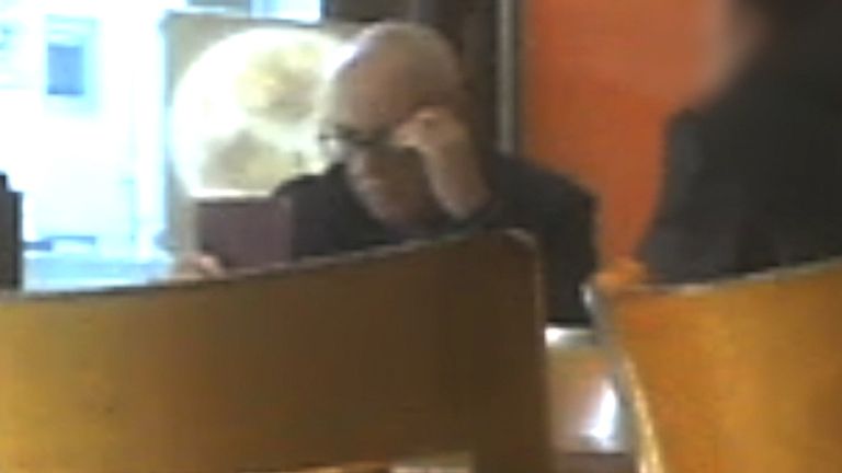 Anthony Beard inspecting a passport at a cafe in New Cross, south London