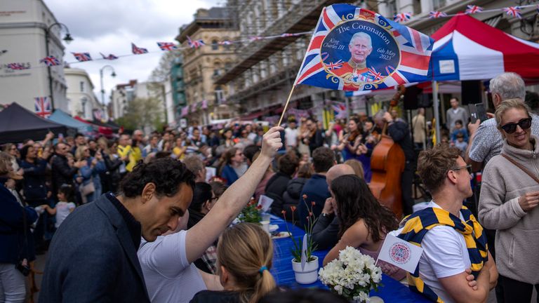 Musicians play their instruments as people sit at long tables to eat their lunch as part of the Big Lunch celebration in London 
Pic:AP