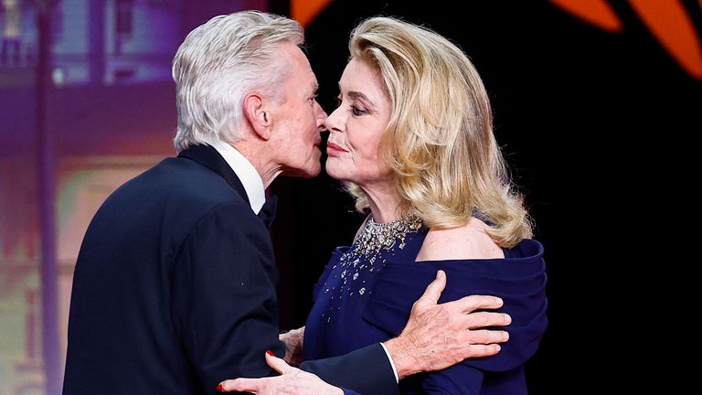 Michael Douglas kisses Catherine Deneuve on stage. 