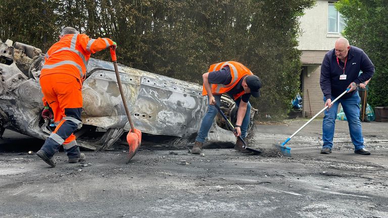 Council workers clear debris from the area immediately around a car that was set alight in Ely, Cardiff, following the riot that broke out after two teenagers died in a crash. Tensions reached breaking point after officers were called to the collision, in Snowden Road, Ely, at about 6pm on Monday. Officers faced what they called "large-scale disorder", with at least two cars torched as trouble involving scores of youths flared for hours. Picture date: Tuesday May 23, 2023.