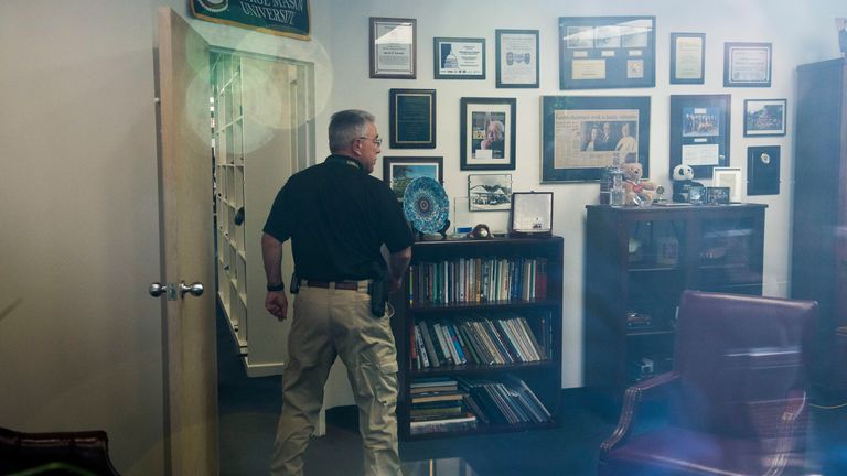 In this image taken through an office window, a law enforcement officer surveys the office of Rep. Gerry Connelly, D-Va., in Fairfax, Va., Monday, May 15, 2023, after police say a man wielding a baseball bat attacked two staffers for Connolly on Monday morning. Fairfax City Police in northern Virginia said in a tweet that a suspect is in custody and the victims are being treated for injuries that are not life-threatening. (AP Photo/Cliff Owen)