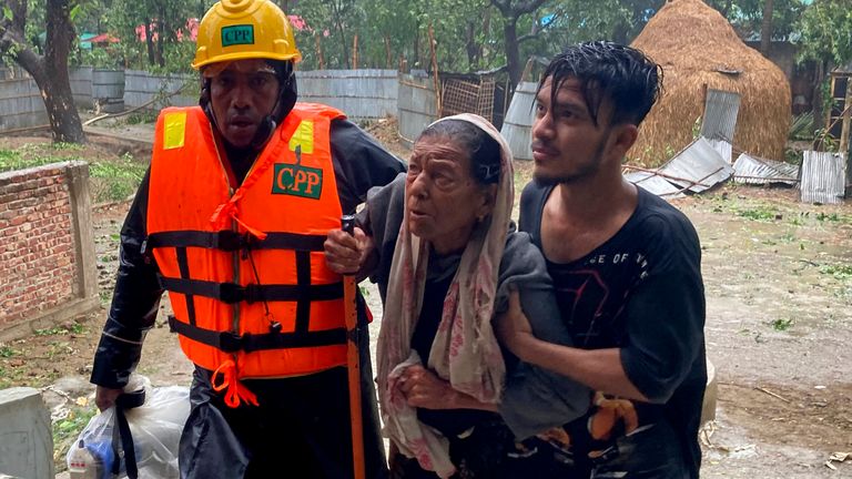 Rescue workers help an elderly woman to reach a makeshift shelter near Cox&#39;s Bazar, Bangladesh.