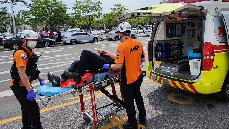 Kurtarma ekipleri, Güney Kore, Daegu'daki Daegu Uluslararası Havalimanı'ndaki bir yolcuyu sedyedeki ambulansa taşıyor Pic:AP