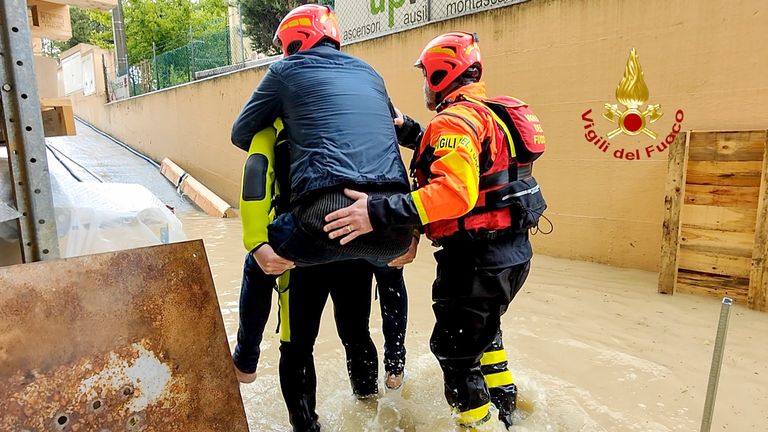 İtalya'nın kuzeyindeki Emilia Romagna bölgesindeki Riccione'de su basmış bir evden bir kişiyi kurtaran itfaiyeciler Pic:Vigili del Fuoco/AP