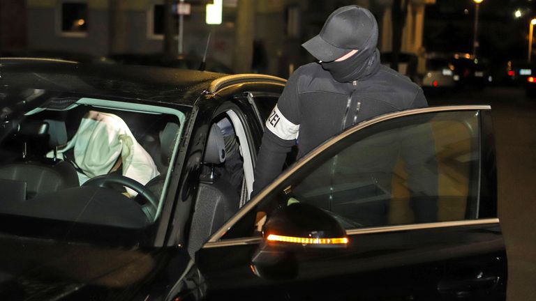 A police officer gets into a car with a suspect during a raid in Hagen Pic:DPA/AP